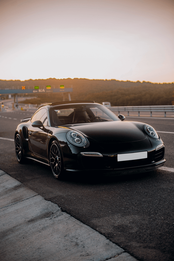 Black sports car on highway at sunset